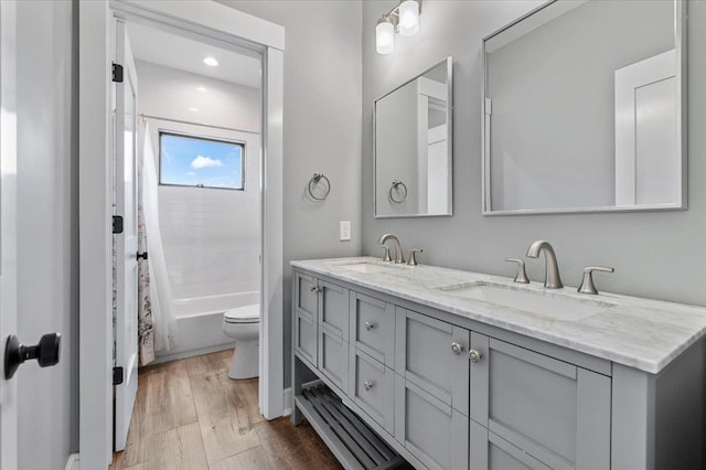 bathroom featuring double vanity, a sink, toilet, and wood finished floors