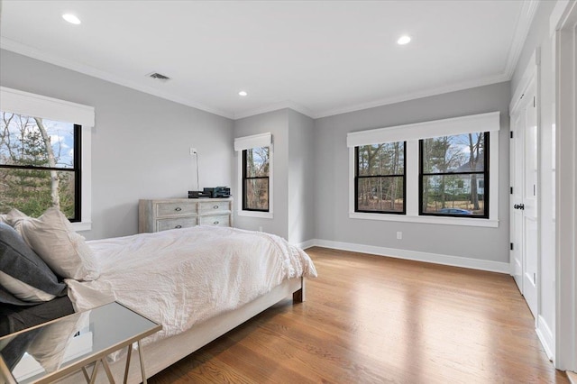 bedroom featuring baseboards, multiple windows, visible vents, and light wood-style floors