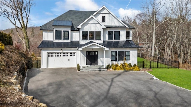 modern inspired farmhouse with a standing seam roof, fence, board and batten siding, and a front yard