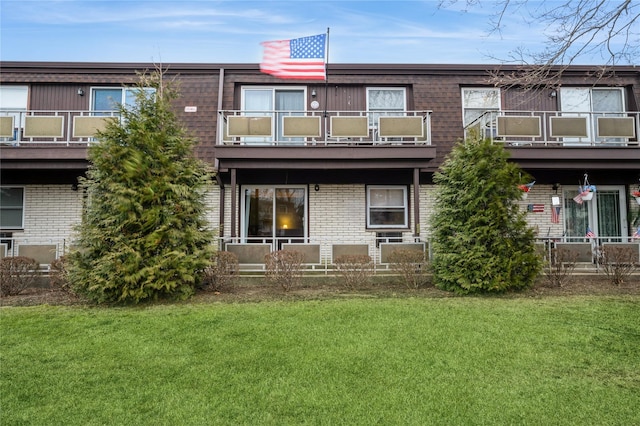 rear view of property featuring brick siding and a yard