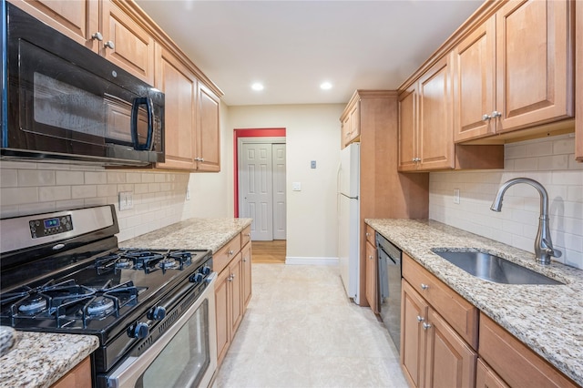 kitchen featuring decorative backsplash, a sink, black appliances, light stone countertops, and baseboards