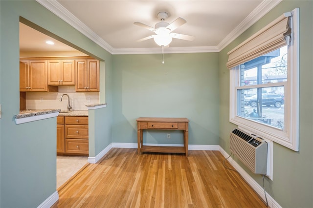 kitchen with light wood finished floors, tasteful backsplash, baseboards, and crown molding