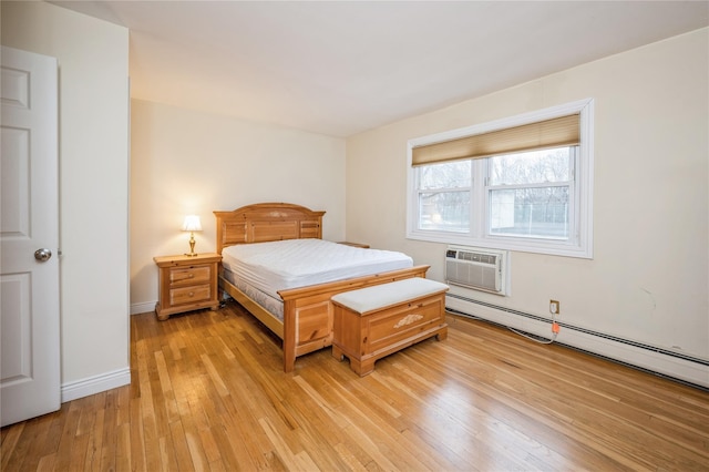 bedroom with a wall unit AC, light wood-type flooring, baseboards, and baseboard heating