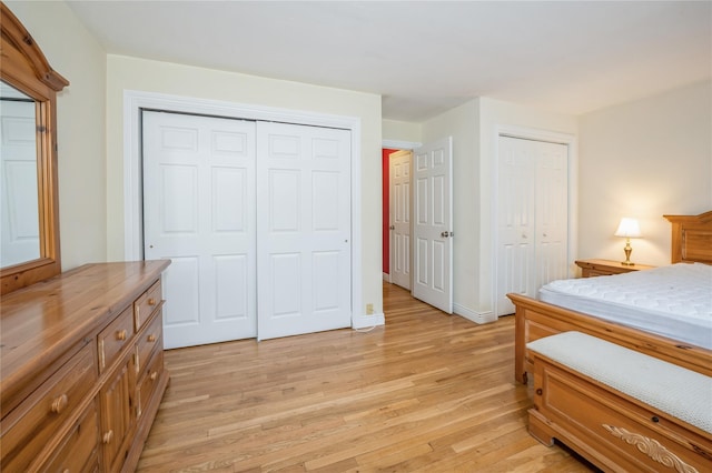 bedroom featuring baseboards, light wood-type flooring, and multiple closets