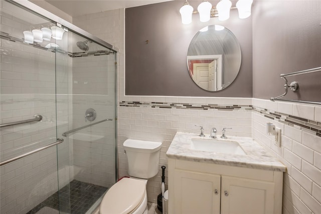 bathroom featuring tile walls, toilet, wainscoting, a shower stall, and vanity