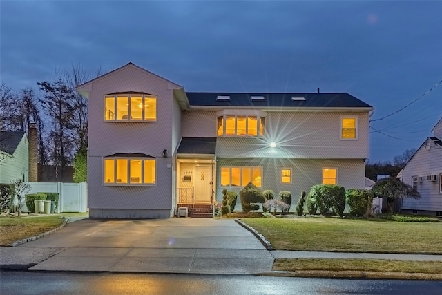 view of front of home with driveway, a front lawn, and fence