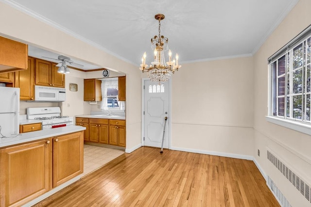 kitchen with radiator, light countertops, brown cabinetry, light wood-type flooring, and white appliances