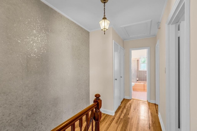 hall with an upstairs landing, baseboards, light wood finished floors, attic access, and crown molding