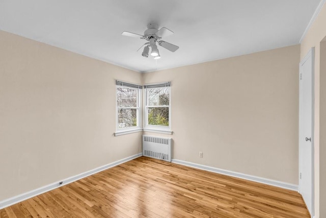 unfurnished room with baseboards, ceiling fan, light wood finished floors, and radiator