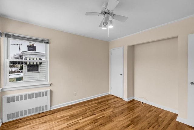 unfurnished room featuring baseboards, a ceiling fan, radiator, wood finished floors, and crown molding