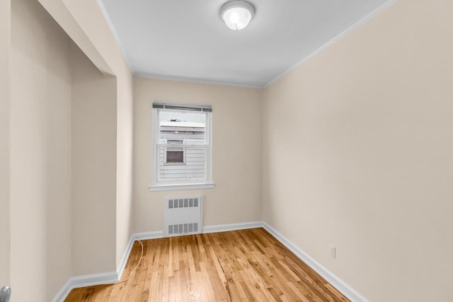 unfurnished room with radiator, light wood-type flooring, baseboards, and ornamental molding