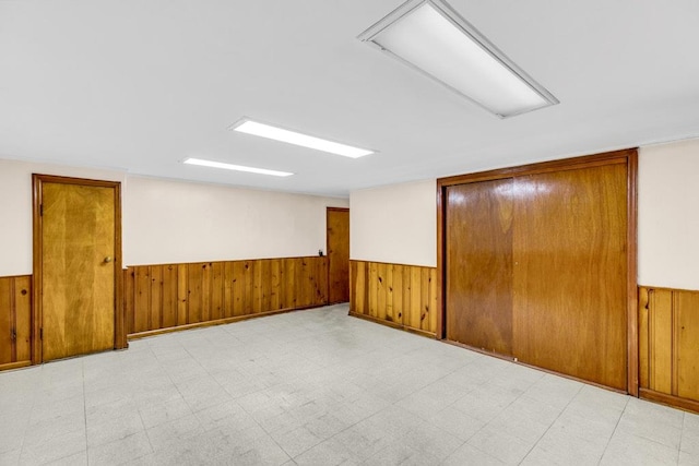 spare room with wainscoting, wood walls, and tile patterned floors