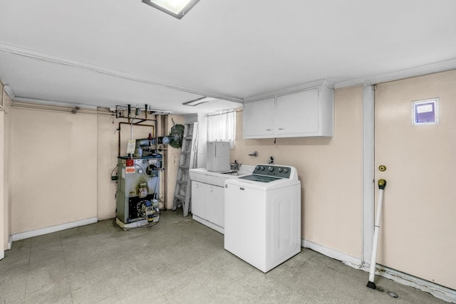 laundry room with light floors, cabinet space, a heating unit, washer / dryer, and baseboards