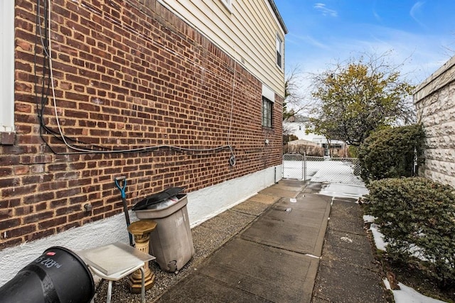 view of side of home with a gate and brick siding