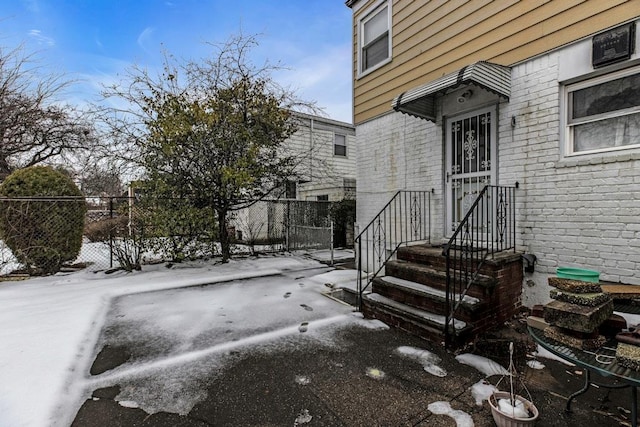 doorway to property featuring brick siding and fence