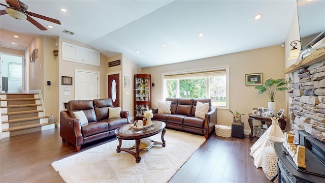 living room with stairs, a fireplace, vaulted ceiling, and wood finished floors