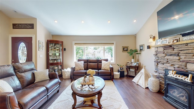 living room featuring dark wood finished floors, a wood stove, vaulted ceiling, and recessed lighting