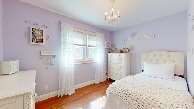 bedroom with an inviting chandelier, baseboards, and wood finished floors