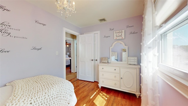 bedroom featuring light wood-type flooring, an inviting chandelier, and visible vents