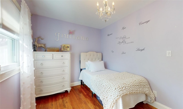 bedroom with an inviting chandelier, baseboards, and wood finished floors