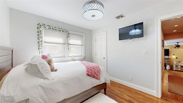 bedroom featuring light wood-style flooring, visible vents, and baseboards