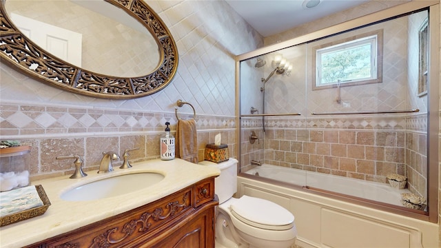 bathroom with toilet, shower / bath combination with glass door, tile walls, and vanity