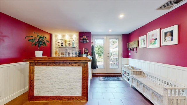 bar with a bar, a wainscoted wall, visible vents, and french doors