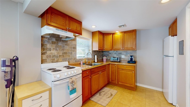 kitchen featuring light countertops, visible vents, a sink, white appliances, and under cabinet range hood