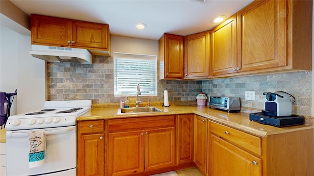 kitchen featuring white range with electric cooktop, decorative backsplash, brown cabinetry, under cabinet range hood, and a sink