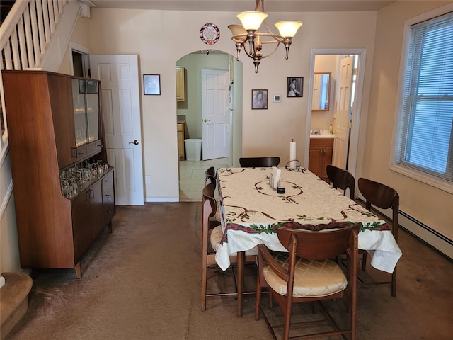 dining space with an inviting chandelier, arched walkways, and dark carpet