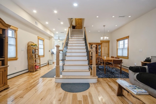 stairs featuring a baseboard radiator, a healthy amount of sunlight, and hardwood / wood-style floors