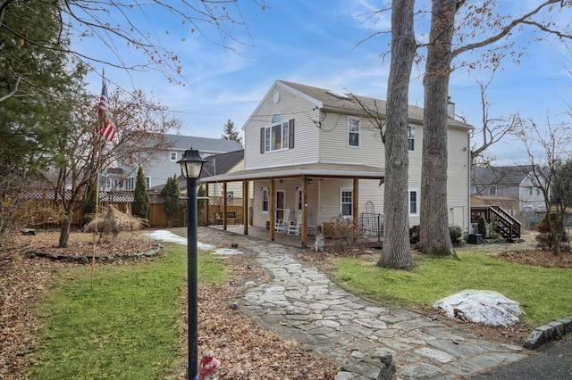 back of property with a lawn, a porch, and fence