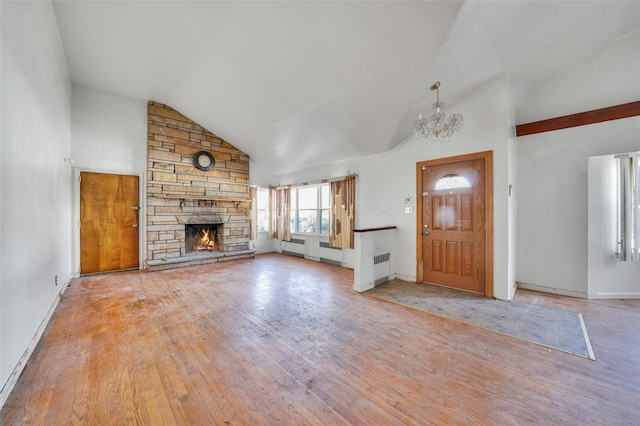 unfurnished living room with baseboards, hardwood / wood-style flooring, a stone fireplace, high vaulted ceiling, and a notable chandelier