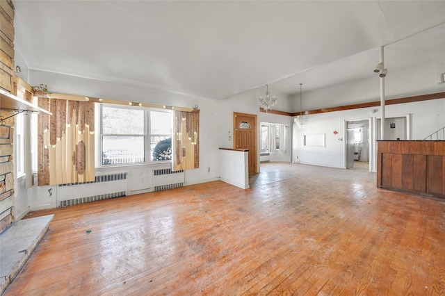 unfurnished living room featuring radiator, wood-type flooring, and vaulted ceiling