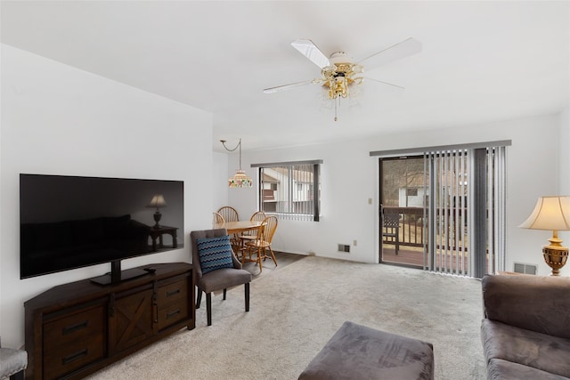 living room featuring ceiling fan, visible vents, and light colored carpet