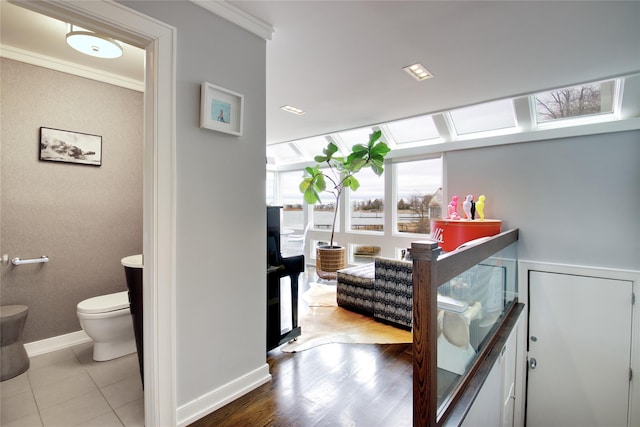 corridor with baseboards, wood finished floors, and crown molding