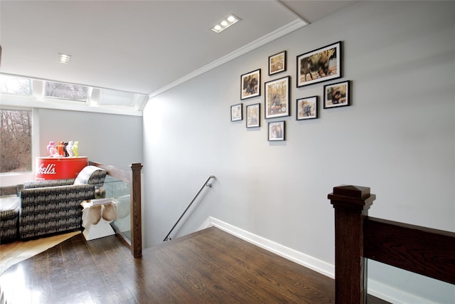 interior space with crown molding, wood finished floors, an upstairs landing, and baseboards