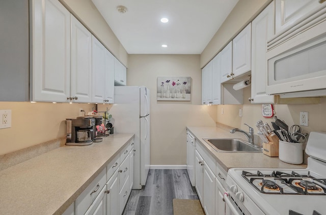 kitchen featuring light countertops, white appliances, white cabinets, and a sink