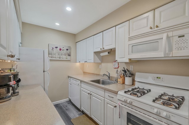 kitchen with white appliances, white cabinetry, light countertops, and a sink