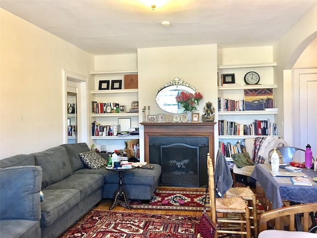 living area with built in features, arched walkways, and a fireplace