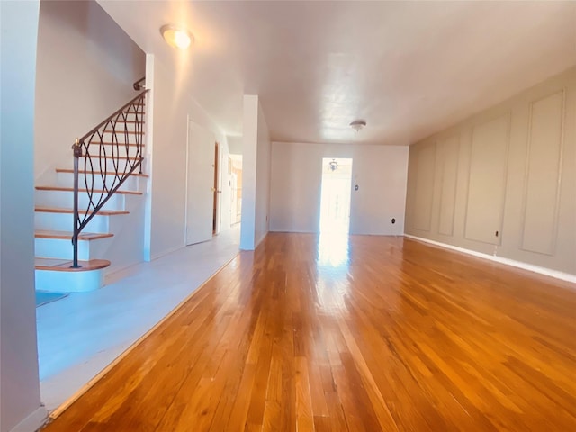 unfurnished living room with wood-type flooring and stairway