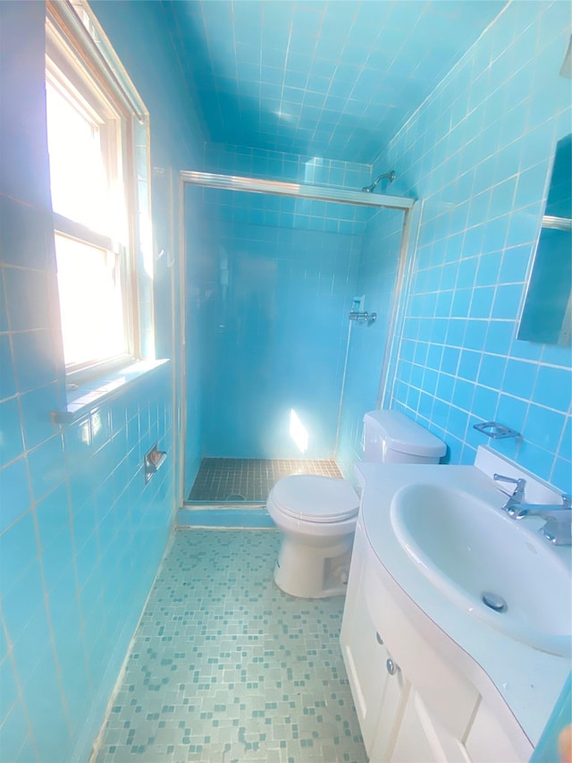 full bath with a shower stall, tile walls, vanity, and toilet