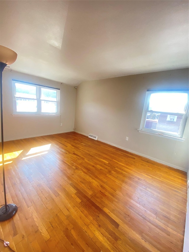 empty room featuring light wood finished floors, visible vents, and baseboards