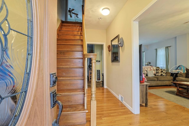 interior space with stairway, light wood-style flooring, visible vents, and baseboards