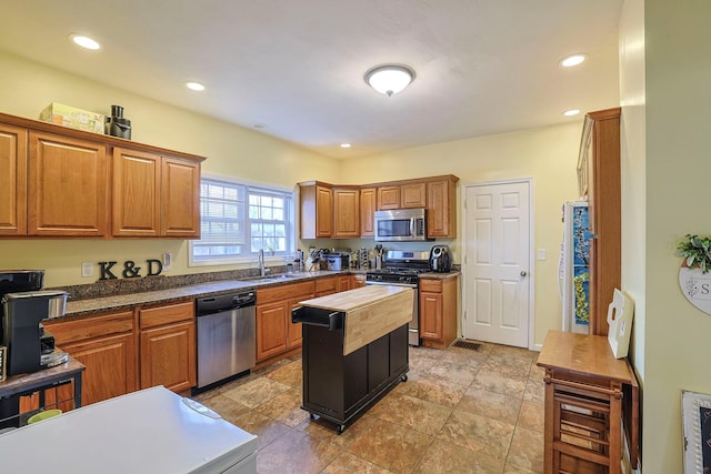 kitchen with brown cabinetry, butcher block counters, stainless steel appliances, a sink, and recessed lighting