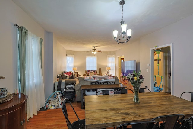 dining room with wood finished floors and ceiling fan with notable chandelier