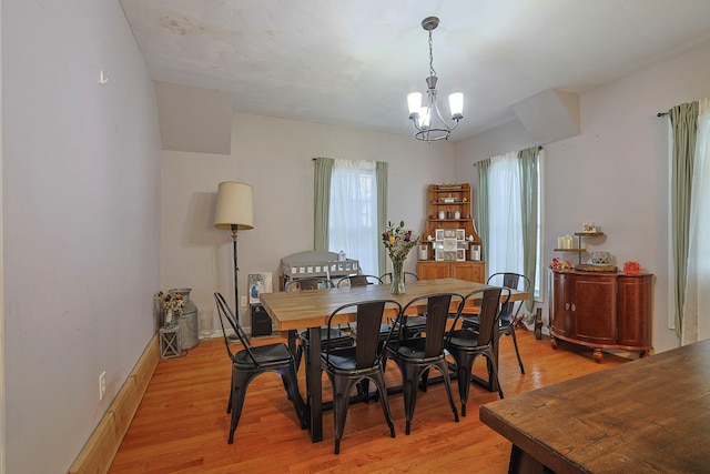 dining room with a notable chandelier, baseboards, and light wood-style floors