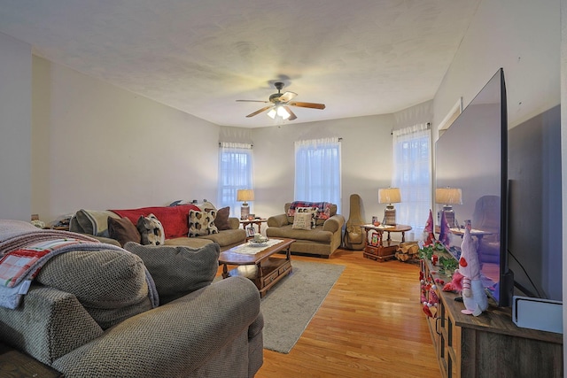 living room featuring light wood-type flooring, a textured ceiling, and a ceiling fan