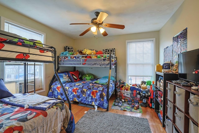 bedroom featuring a ceiling fan, multiple windows, and wood finished floors