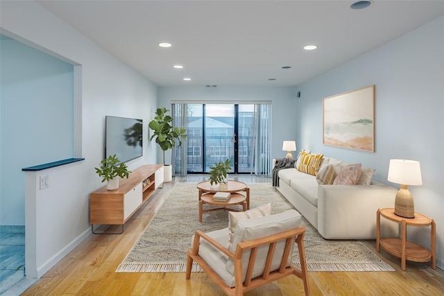 living room featuring baseboards, light wood-style flooring, and recessed lighting